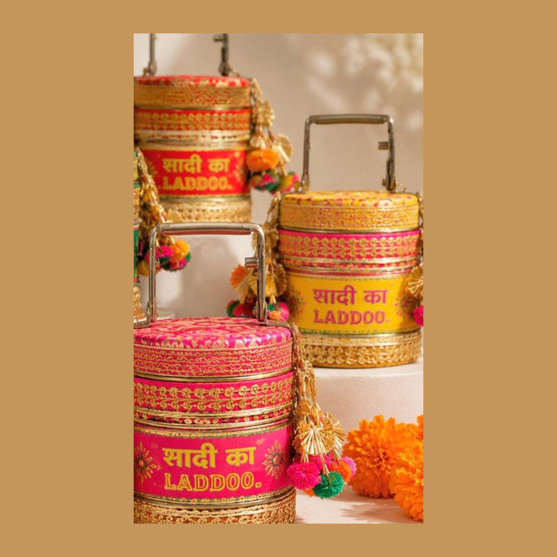 Brocade-wrapped tiffins lettered Shaadi ka Laddoo, hung with marigolds and tassels